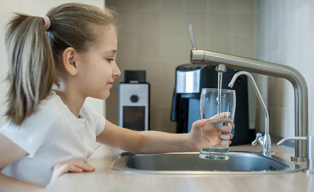 Mädchen füllt sich Wasserglas